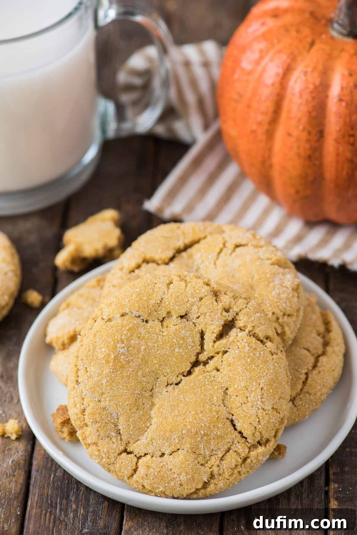 Cozy Pumpkin Cookie Bliss 6 a few pumpkin sugar cookies on white plate with a glass of milk and pumpkin in the background