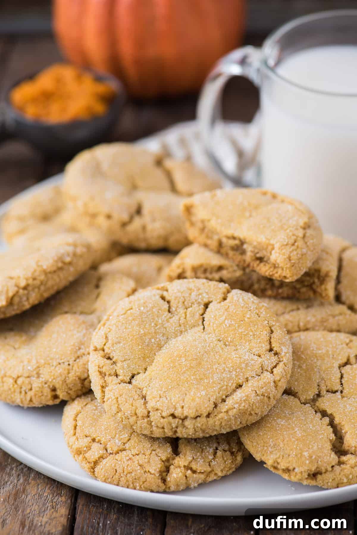 Cozy Pumpkin Cookie Bliss 8 pumpkin cookies piled on white serving tray with a glass of milk and pumpkin in the background