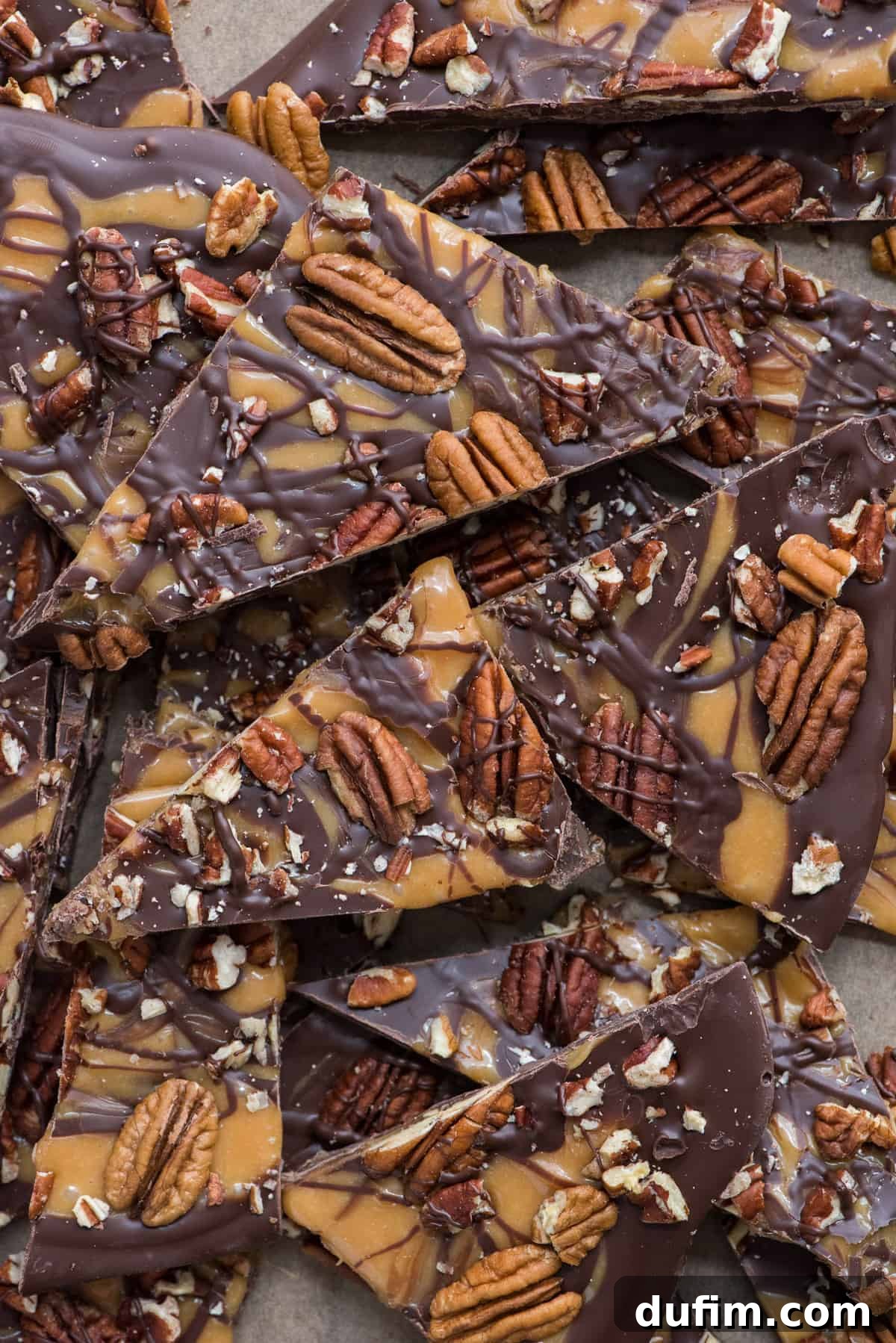 Turtle bark with chocolate, caramel and pecans broken into pieces on brown parchment paper