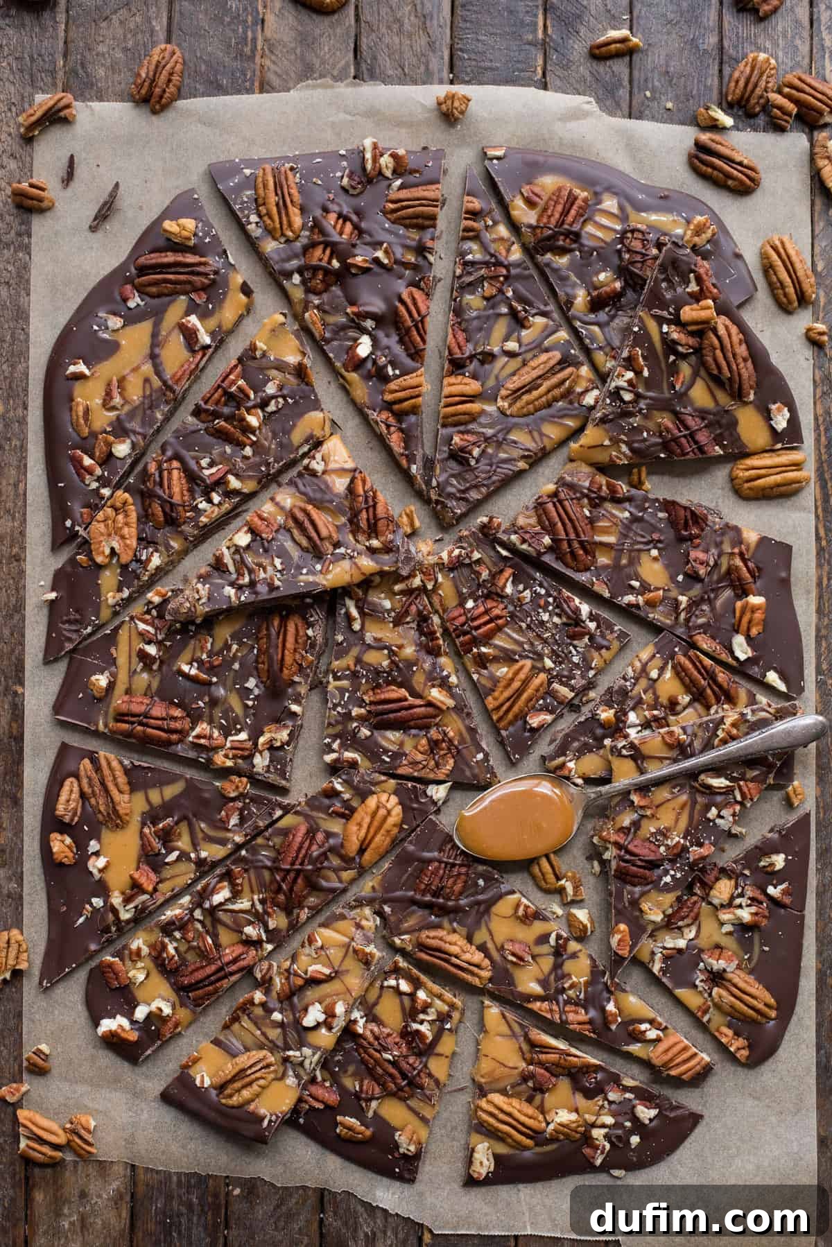 Turtle bark with chocolate, caramel and pecans broken into pieces on brown parchment paper