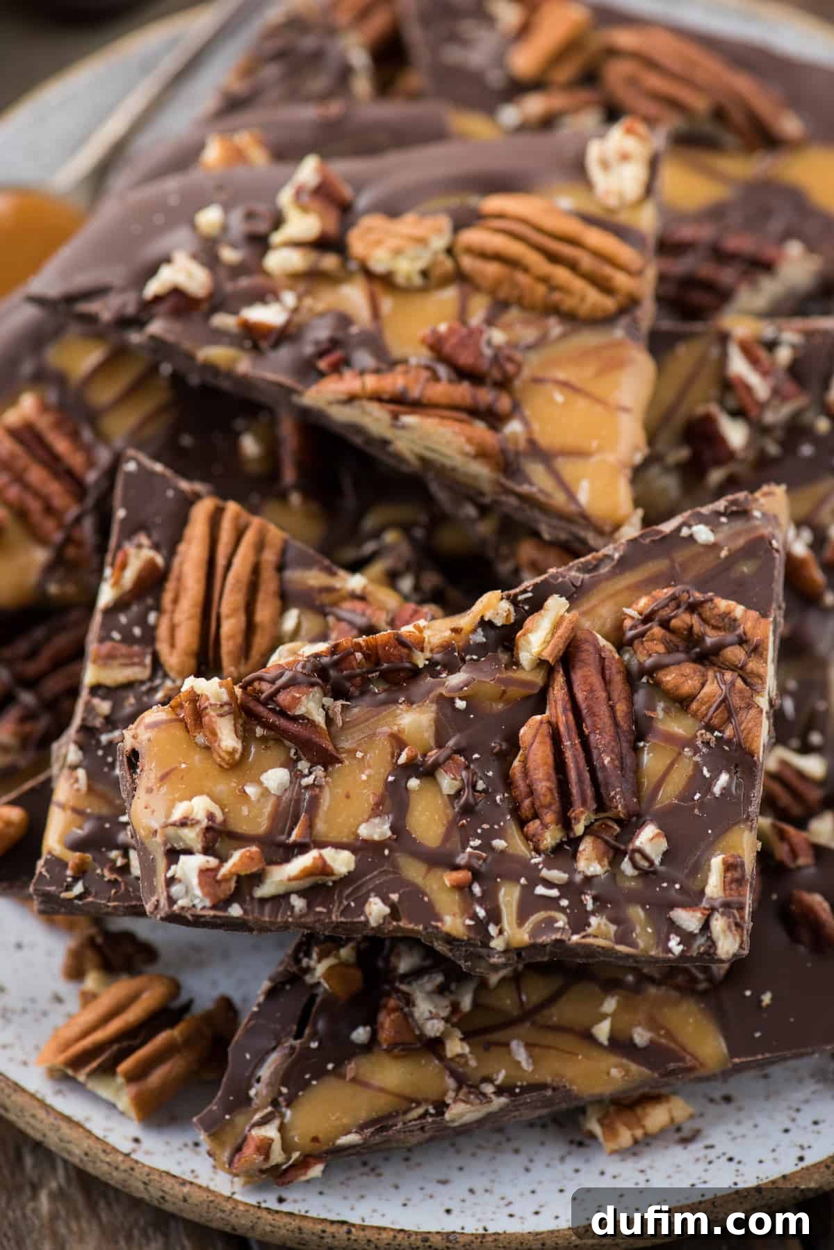 Turtle bark with chocolate, caramel and pecans broken into pieces on white plate