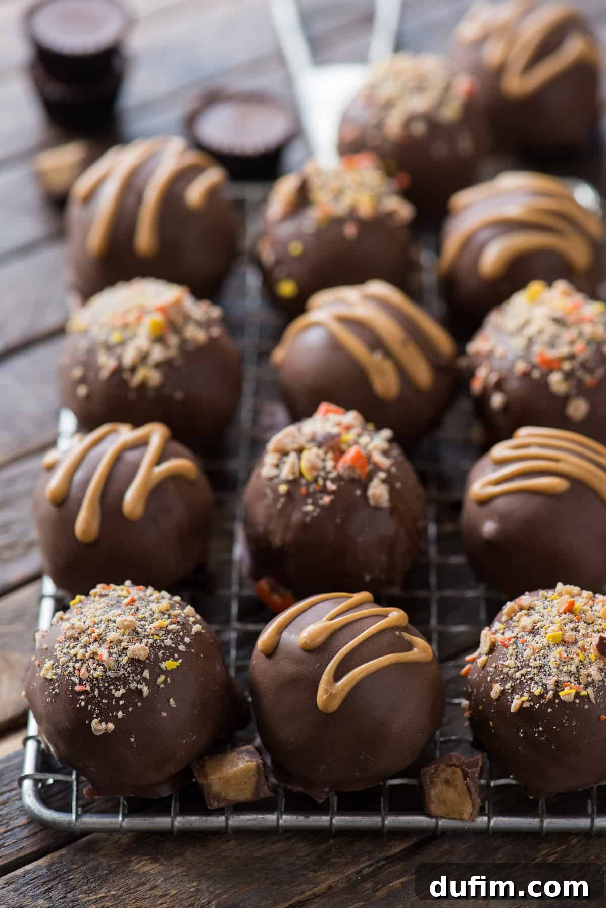 Reese's Peanut Butter Oreo Truffles 3 Freshly dipped Reese's Oreo balls, adorned with peanut butter drizzle, cooling on a metal rack set against a warm wood background, showcasing their irresistible appeal.