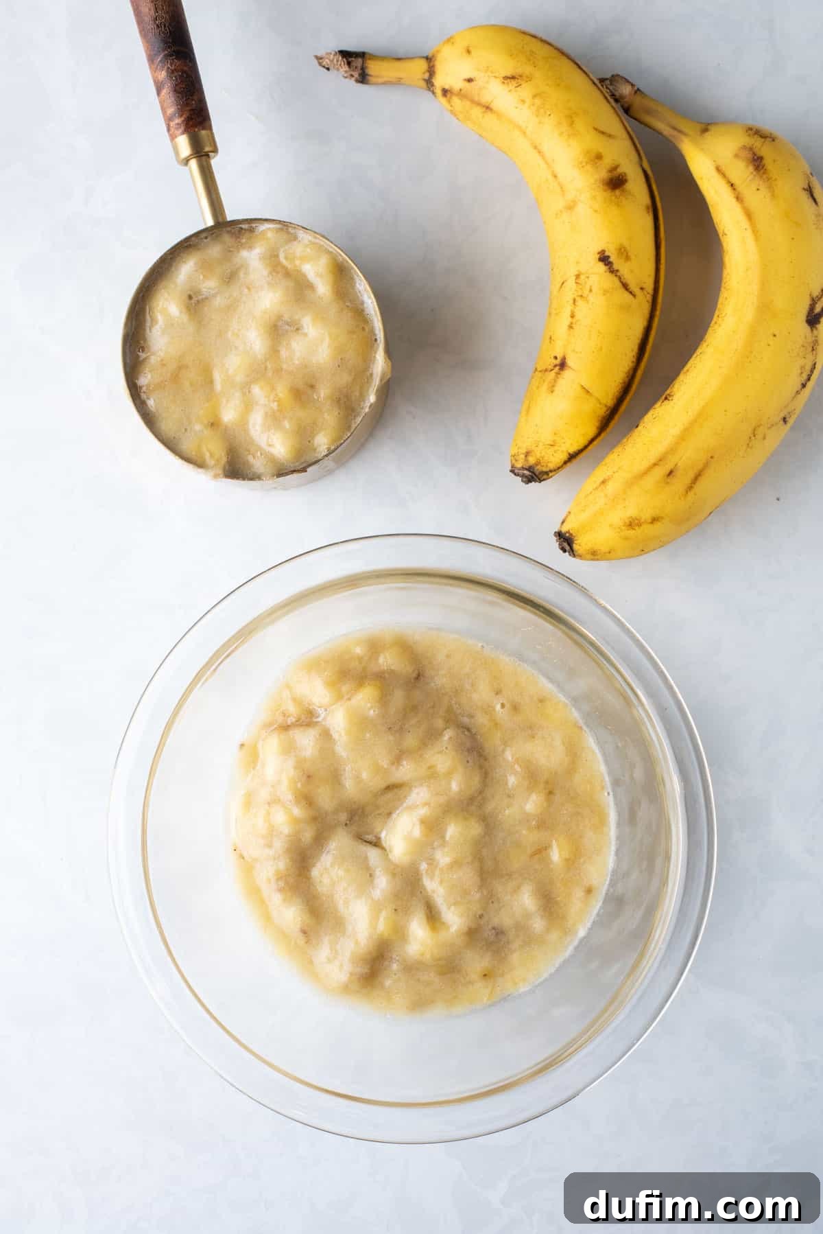 mashed bananas in glass bowl and in measuring cup