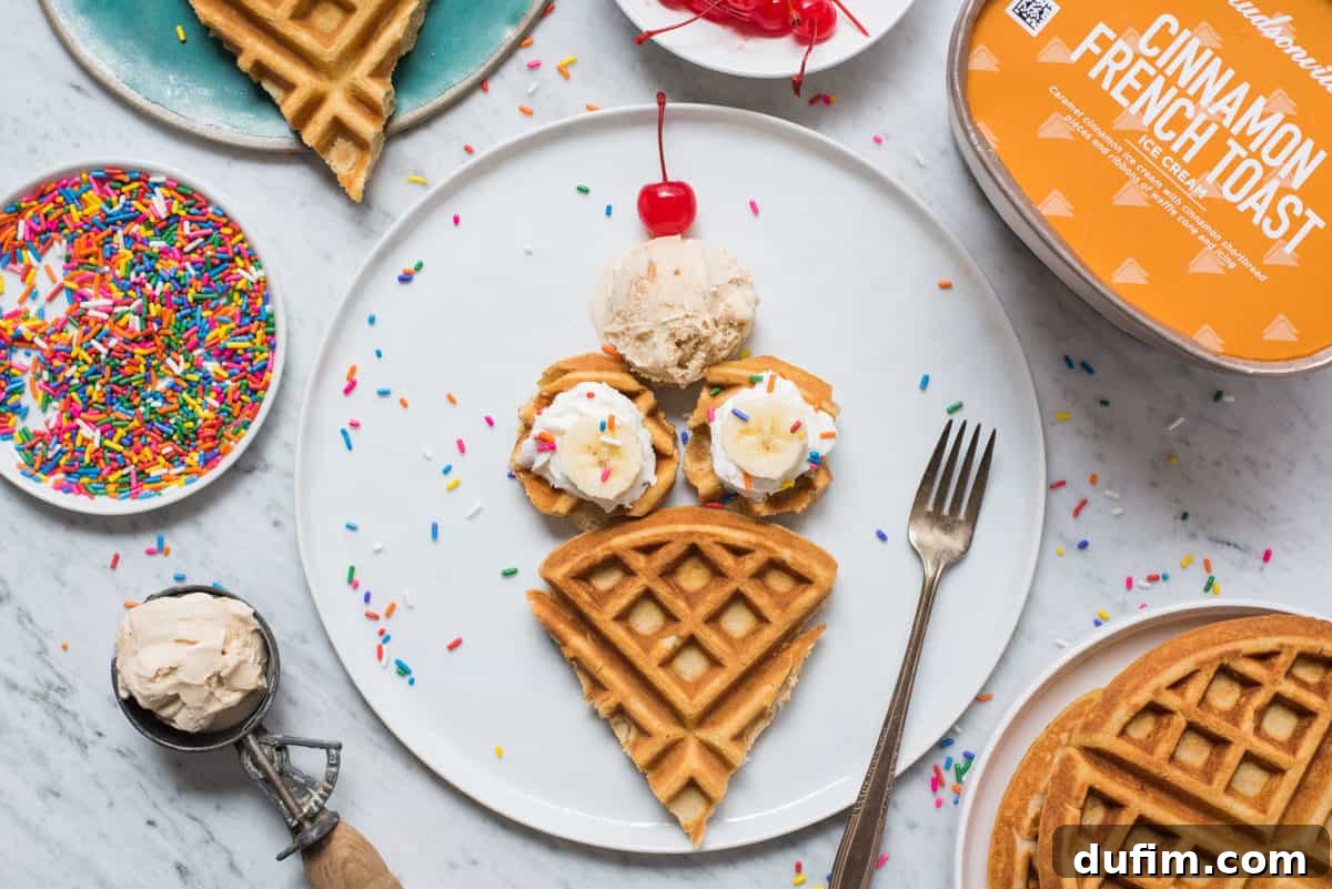 Close-up of waffles shaped like ice cream cones on a white plate, garnished with whipped cream, banana slices, and colorful sprinkles, ready to be served.