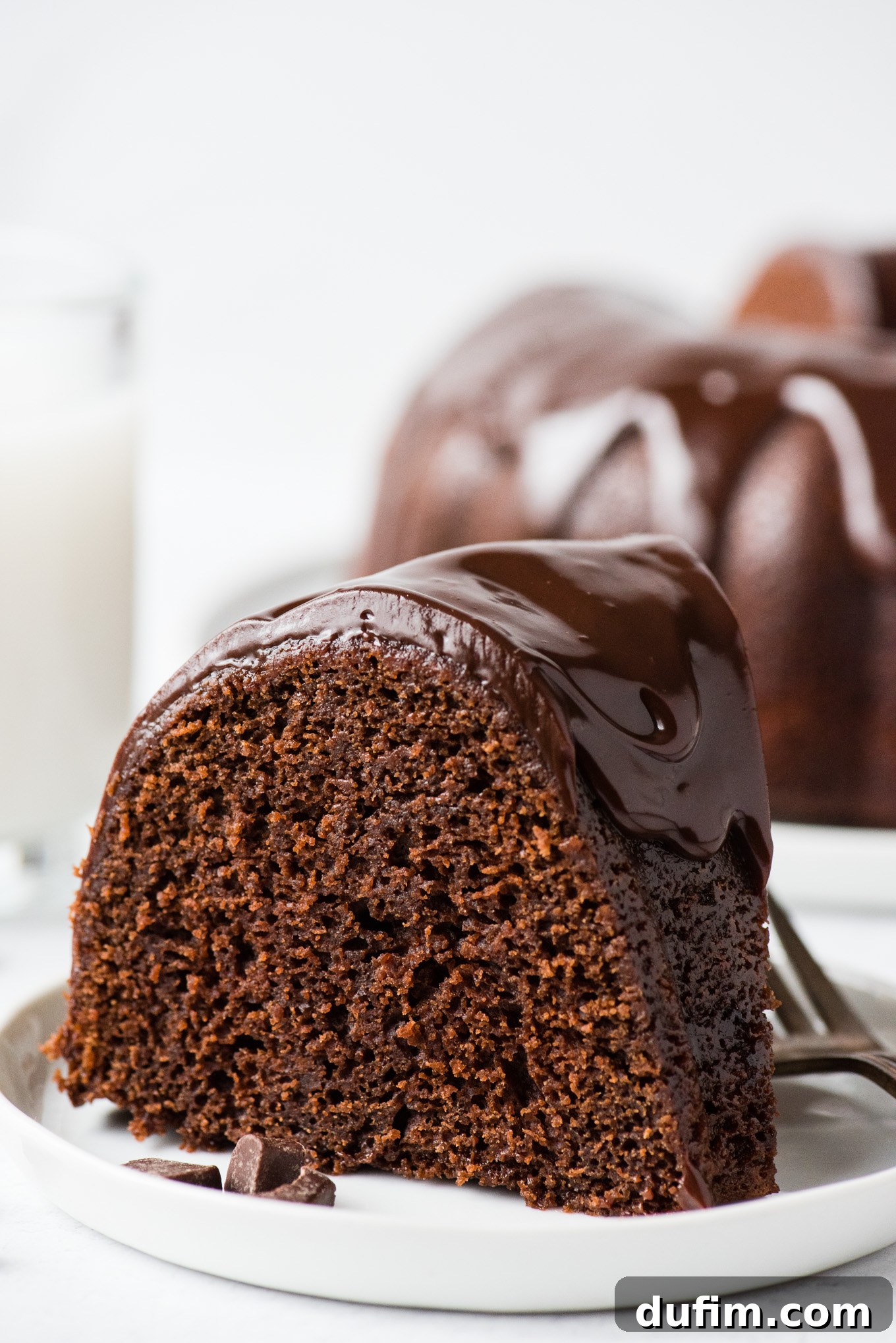 Decadent Chocolate Bundt with a Glossy Glaze 4 A perfectly baked slice of chocolate bundt cake, richly coated in smooth chocolate glaze, served on a pristine white plate, ready to be enjoyed.
