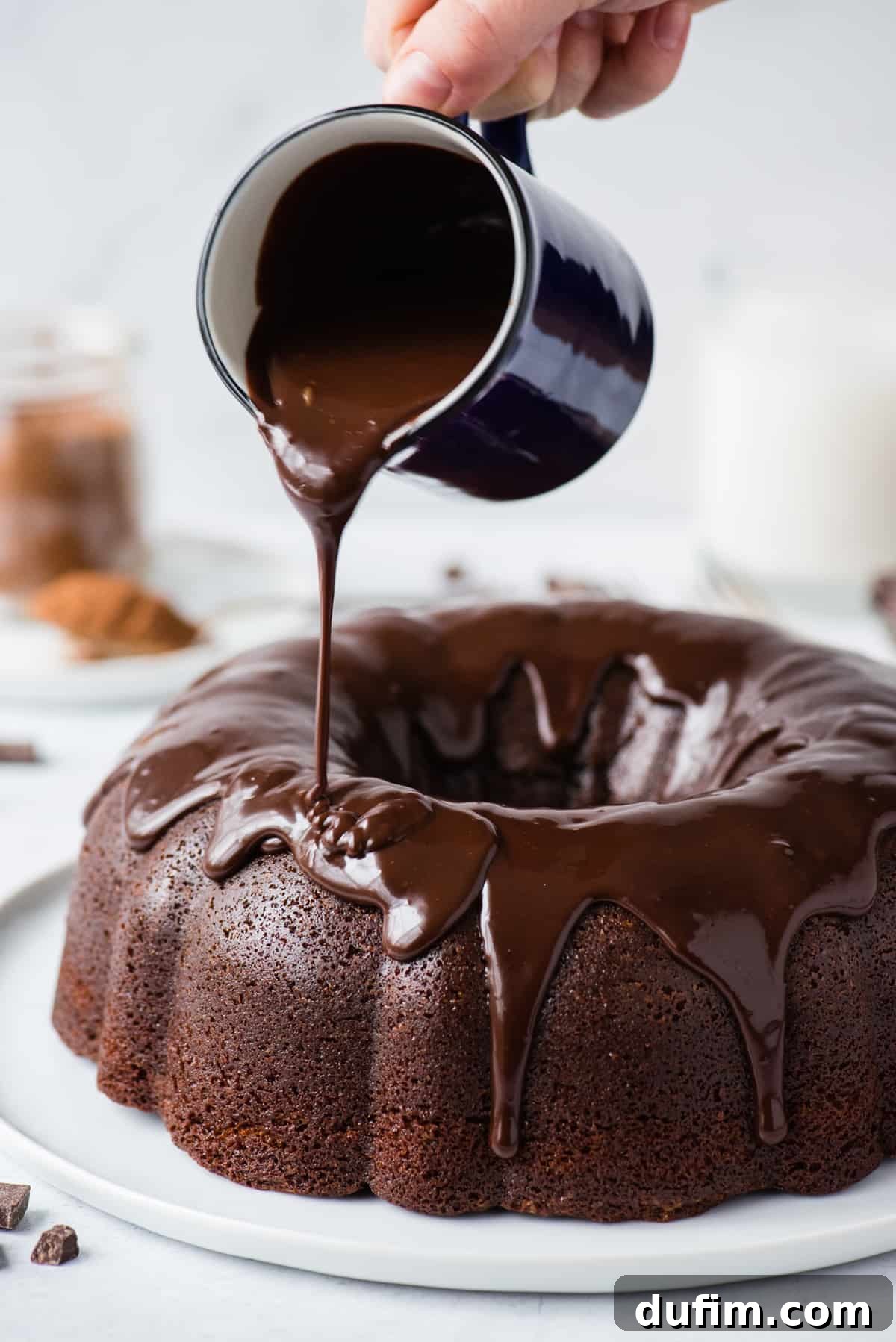 Decadent Chocolate Bundt with a Glossy Glaze 5 Rich, glossy chocolate glaze being poured artfully over a freshly baked chocolate bundt cake, creating tempting drips down the sides, set against a pristine white background.