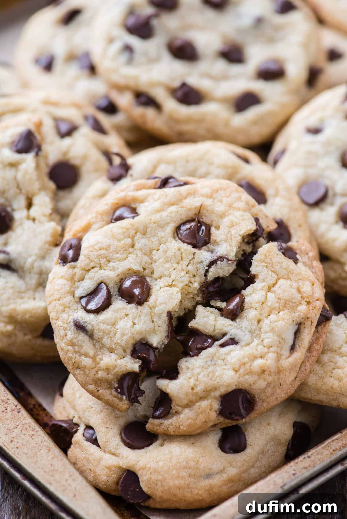 A close-up shot of a perfectly baked chocolate chip cookie, broken in half, revealing a delightfully gooey, melted chocolate center and a soft, chewy texture.