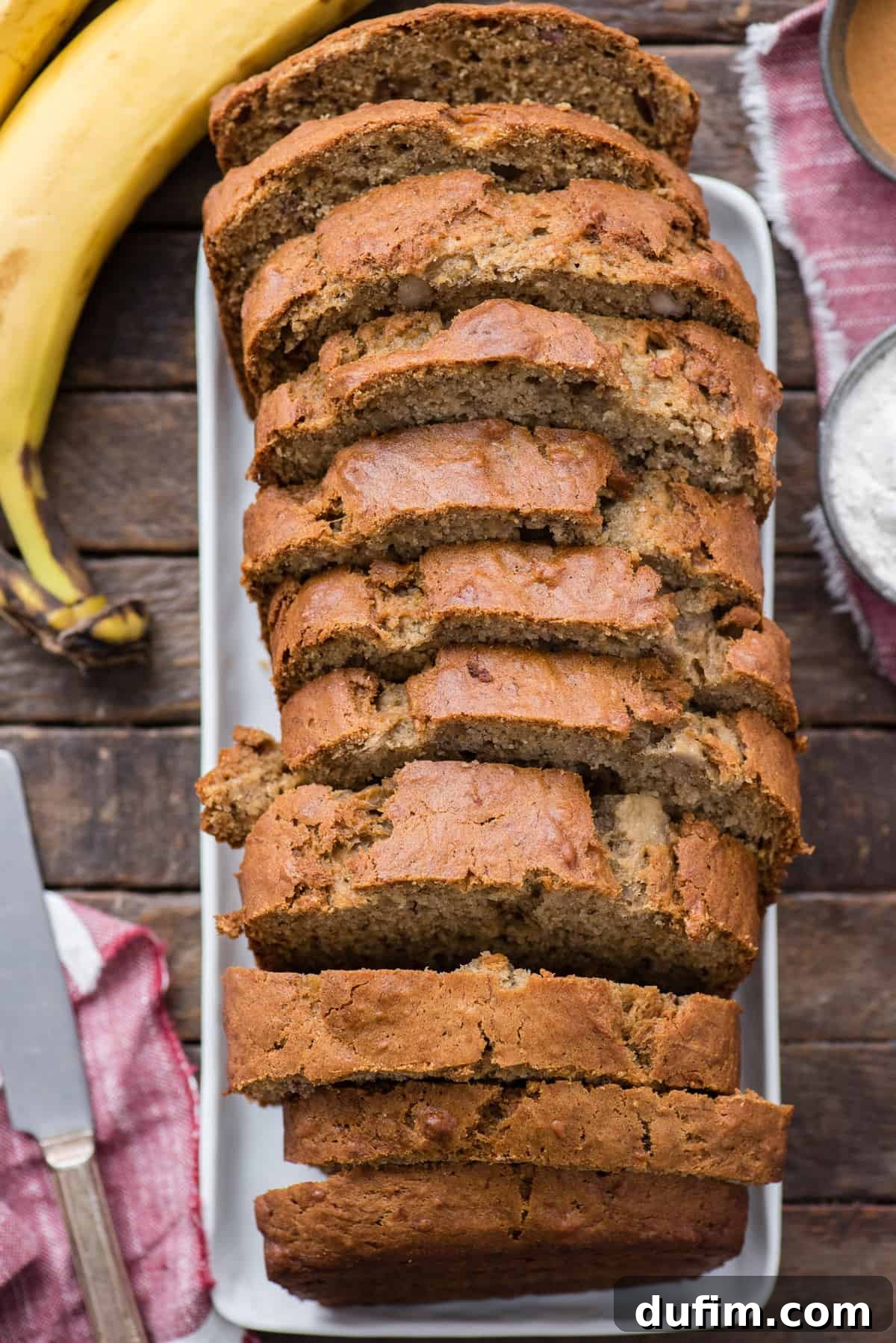 sliced banana bread on white platter on wood background