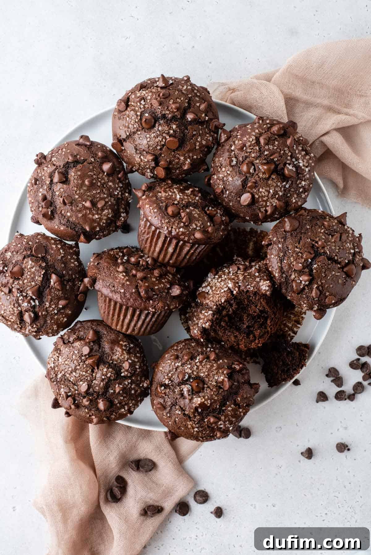 Decadent Chocolate Muffins 4 A beautiful arrangement of freshly baked double chocolate chip muffins, perfectly domed and sprinkled with sugar, presented on a pristine white serving tray.