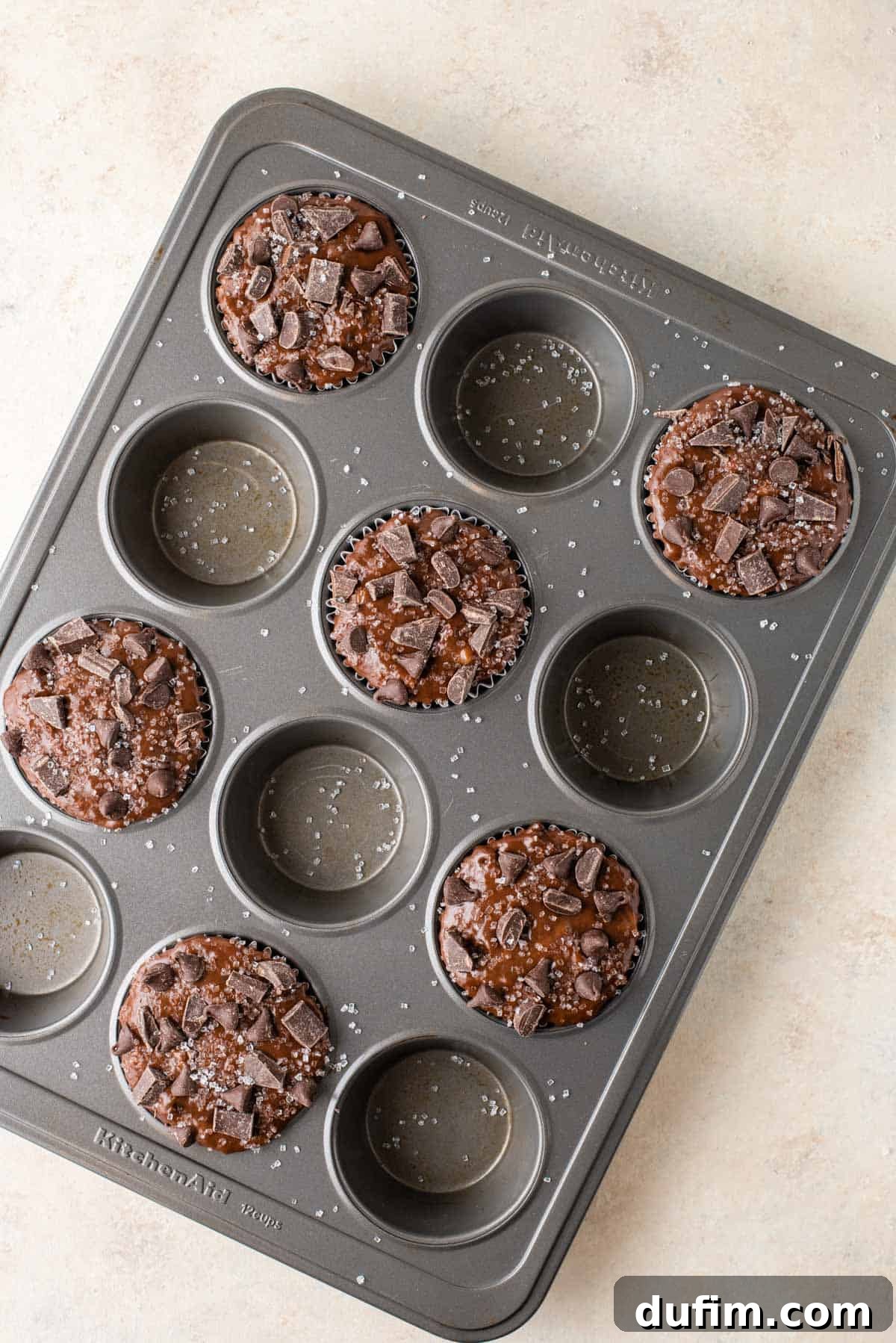 Decadent Chocolate Muffins 6 A muffin pan shows a strategic arrangement: only every other cup is filled with rich chocolate batter, a technique for achieving perfect bakery-style muffin tops.