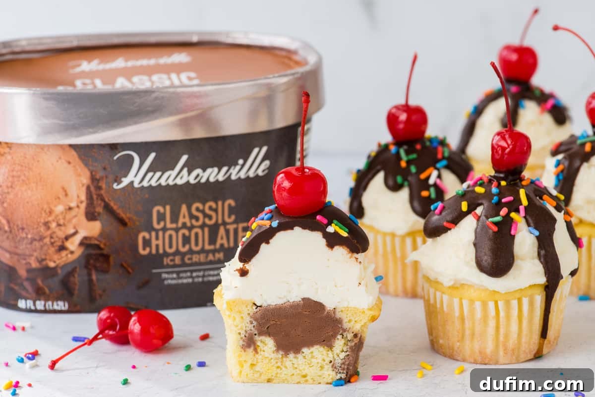 Arrangement of finished ice cream cupcakes on a white surface, with a container of Hudsonville ice cream visible in the soft-focus background, highlighting the key ingredient.
