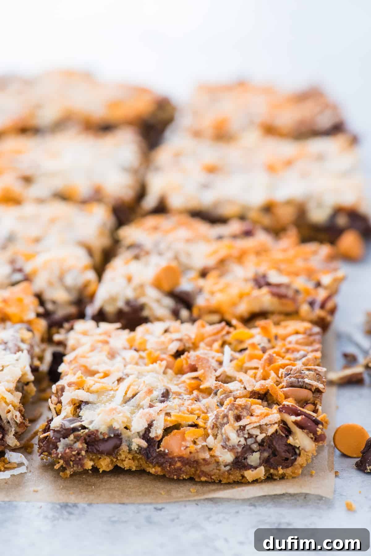 7 layer cookie bars cut into squares on brown parchment paper