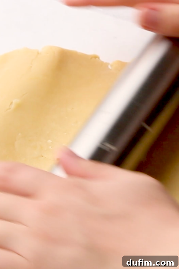 Cream cheese frosting being spread onto the cooled fruit pizza crust.