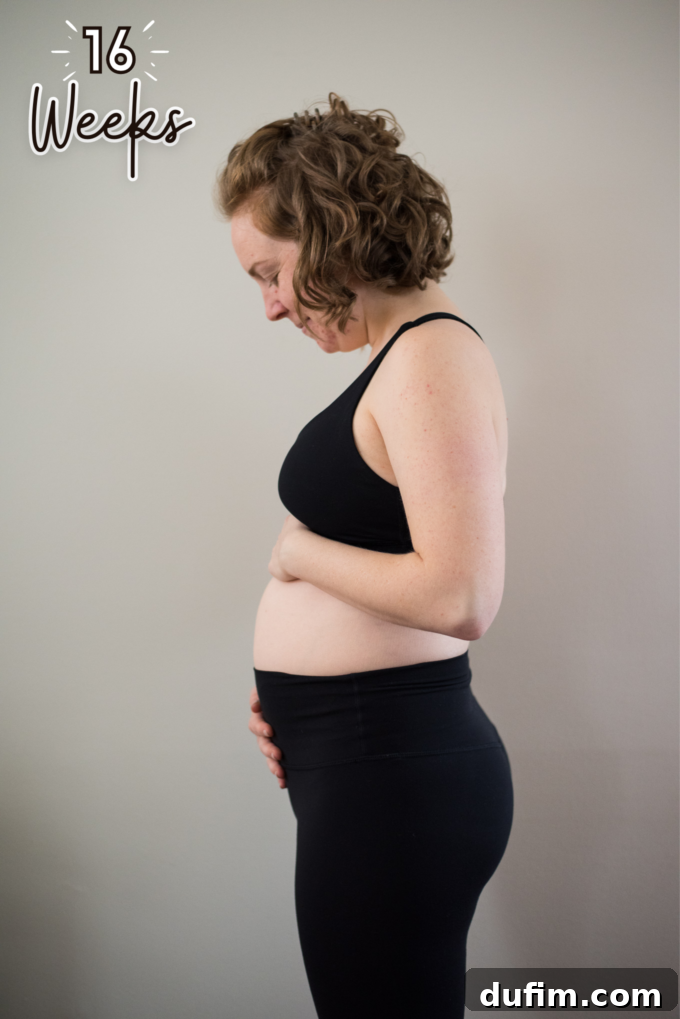 Pregnant woman smiling, showcasing her baby bump in a casual setting.