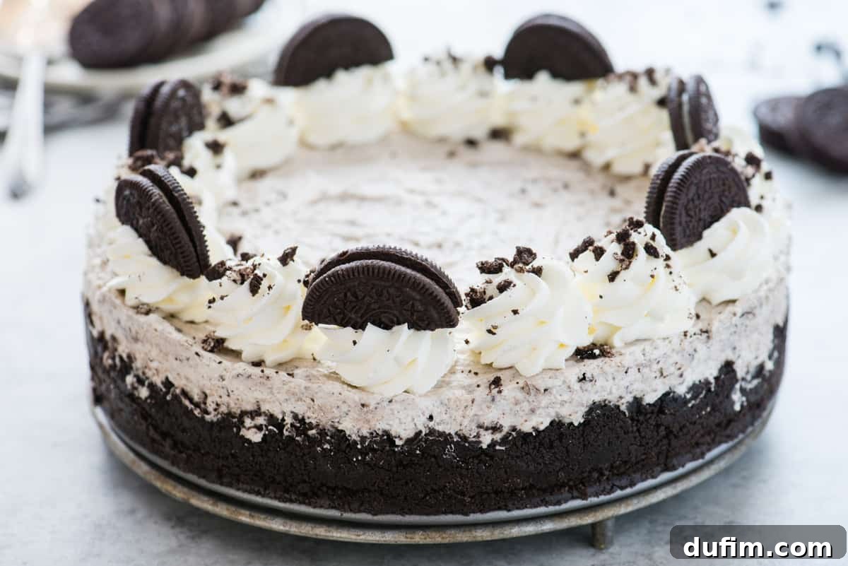 A whole no-bake Oreo cheesecake, beautifully topped with swirls of homemade whipped cream and generous pieces of crushed Oreos, presented on a pristine white background. It promises a decadent, yet easy-to-make dessert.