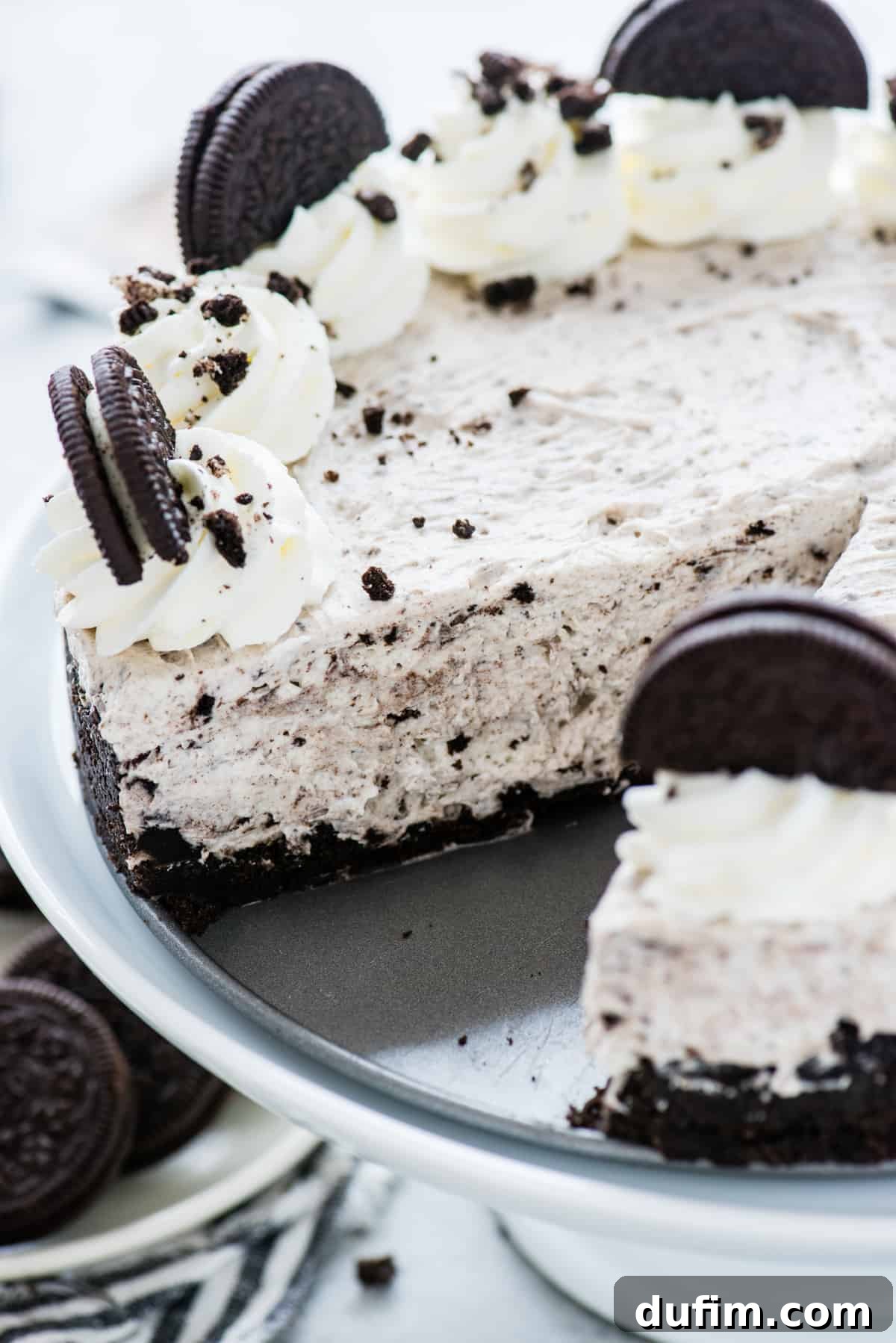A no-bake Oreo cheesecake resting in a springform pan with one perfect slice already removed, highlighting the smooth, creamy filling and crunchy Oreo crust.