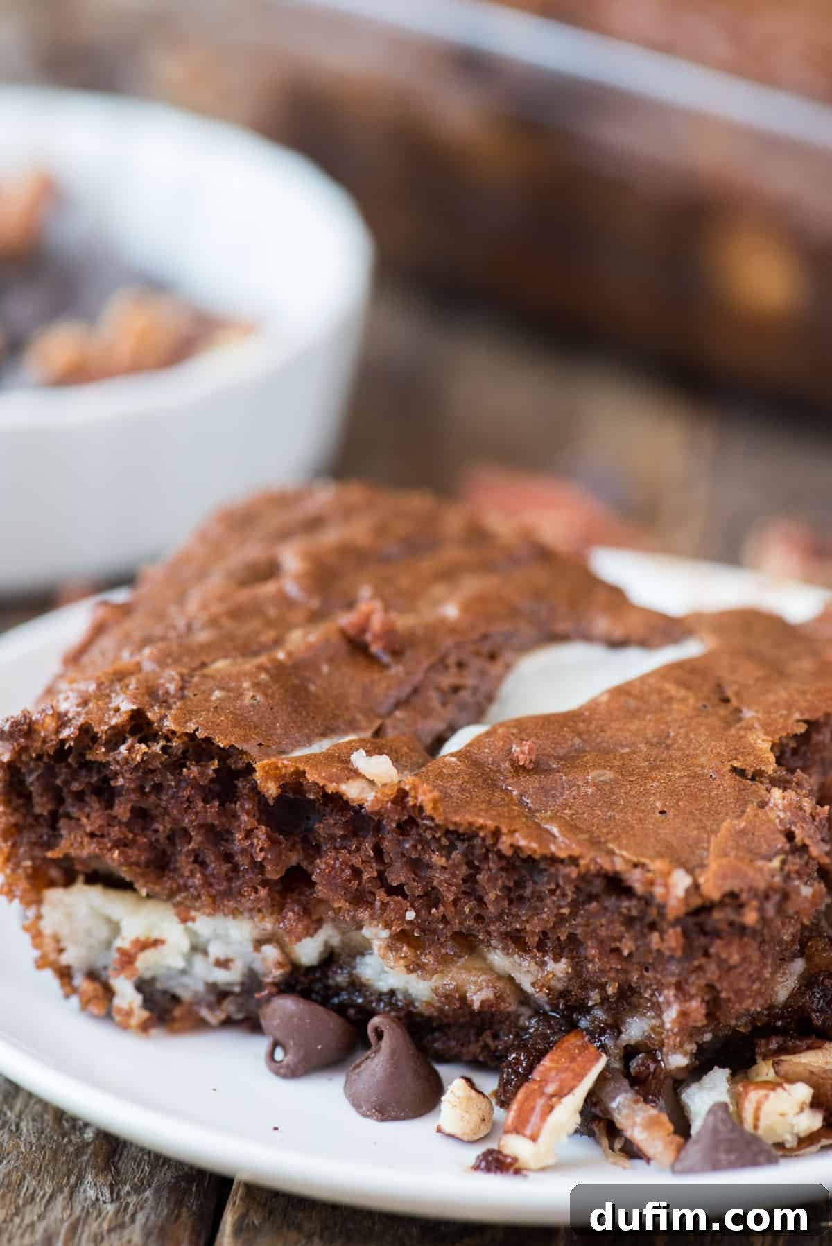 A slice of Earthquake Cake on a white plate, showcasing its rich chocolate base, coconut, pecans, and creamy, gooey baked-in swirl.