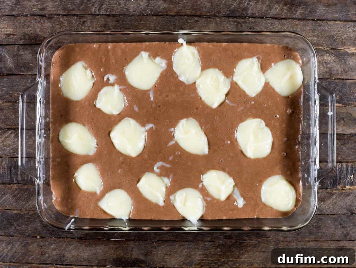 A large rectangular Earthquake Cake, showcasing its deep color, scattered toppings, and creamy swirl.