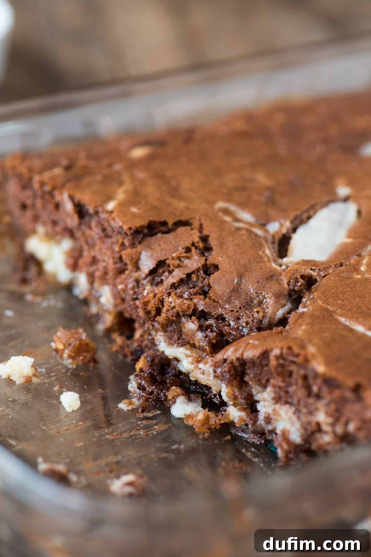 A slice of Earthquake Cake served in a clear glass cake pan, highlighting the layers and gooey texture.