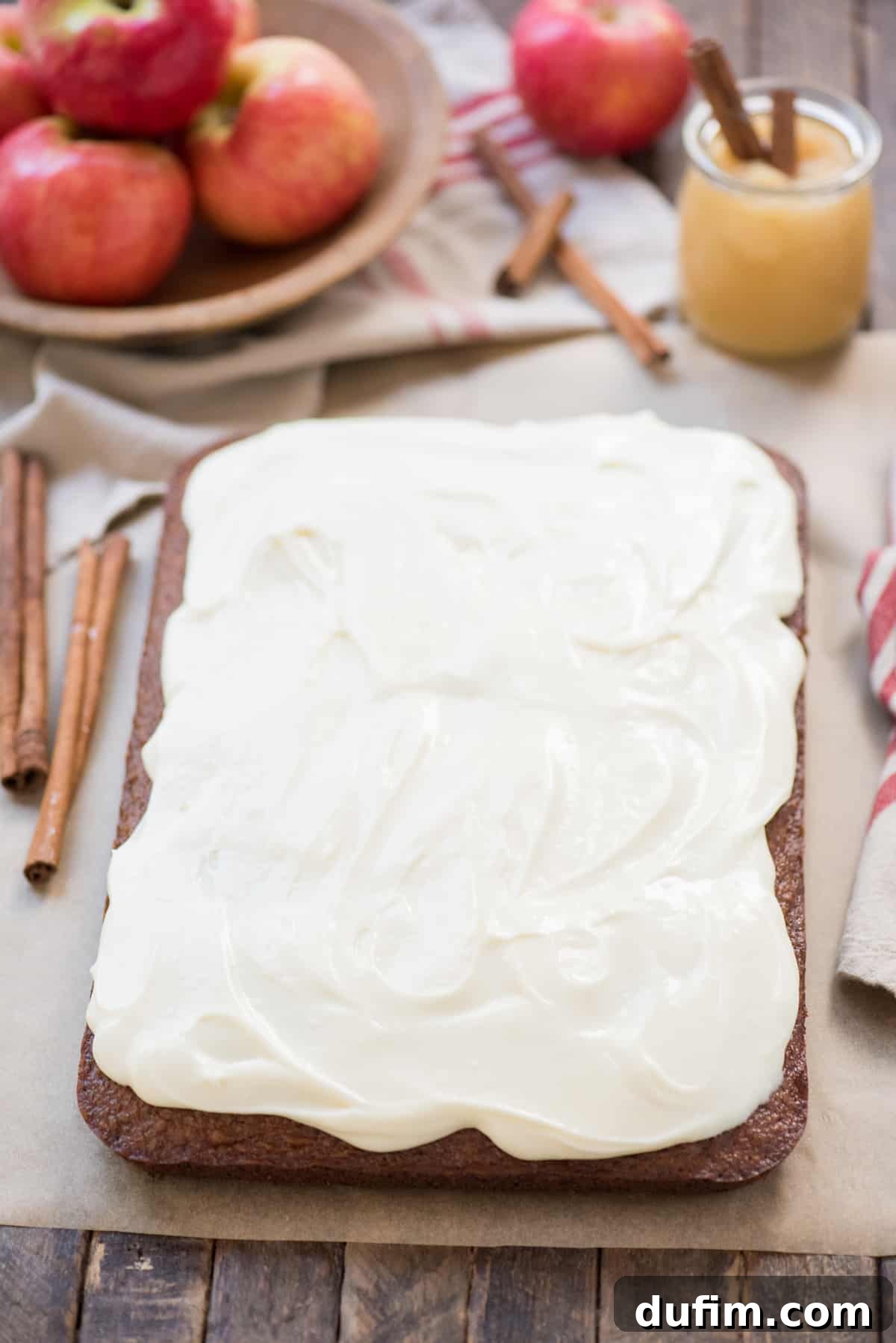 Warm Applesauce Spice Cake 3 A perfectly baked applesauce cake, still in its 9x13 inch pan, generously topped with a swirl of creamy white cream cheese frosting, ready to be served.