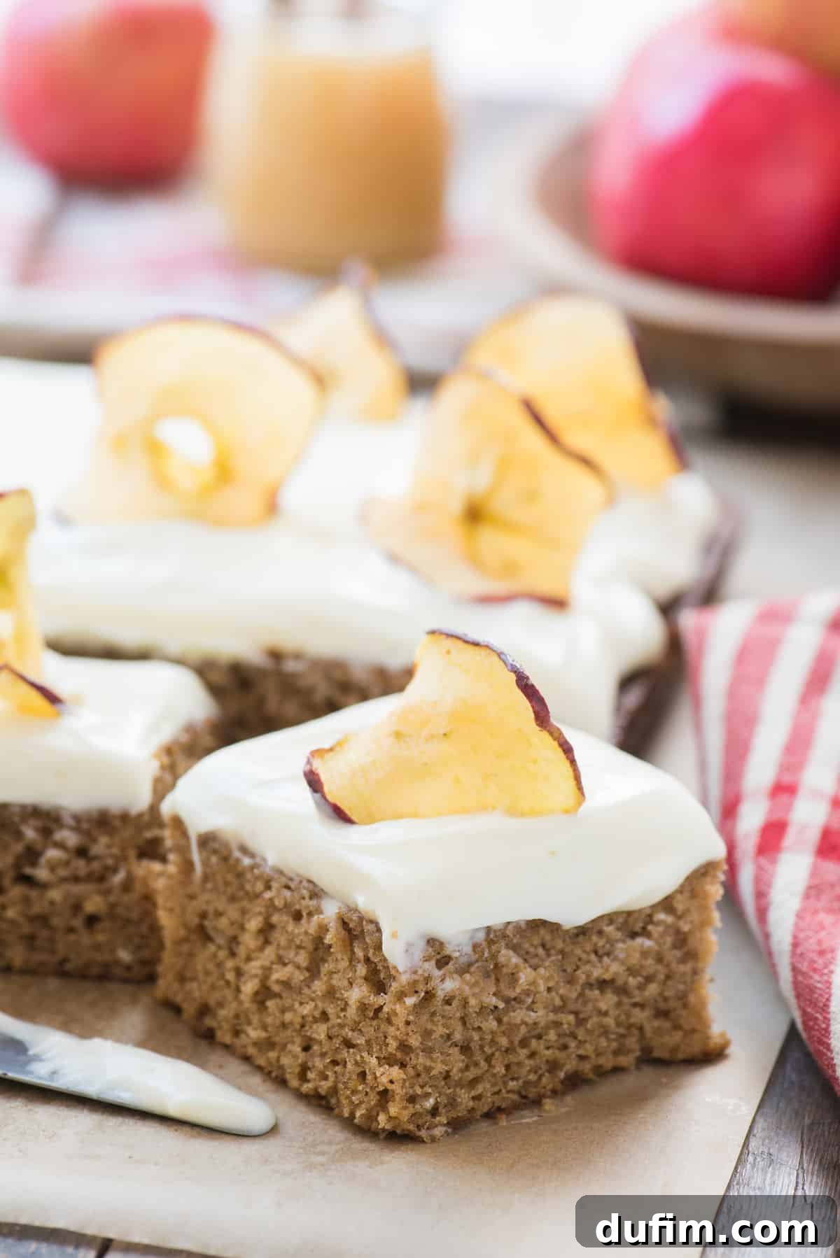 Warm Applesauce Spice Cake 4 A delicious slice of applesauce cake with luscious cream cheese frosting, resting on brown parchment paper, highlighting its tender texture.