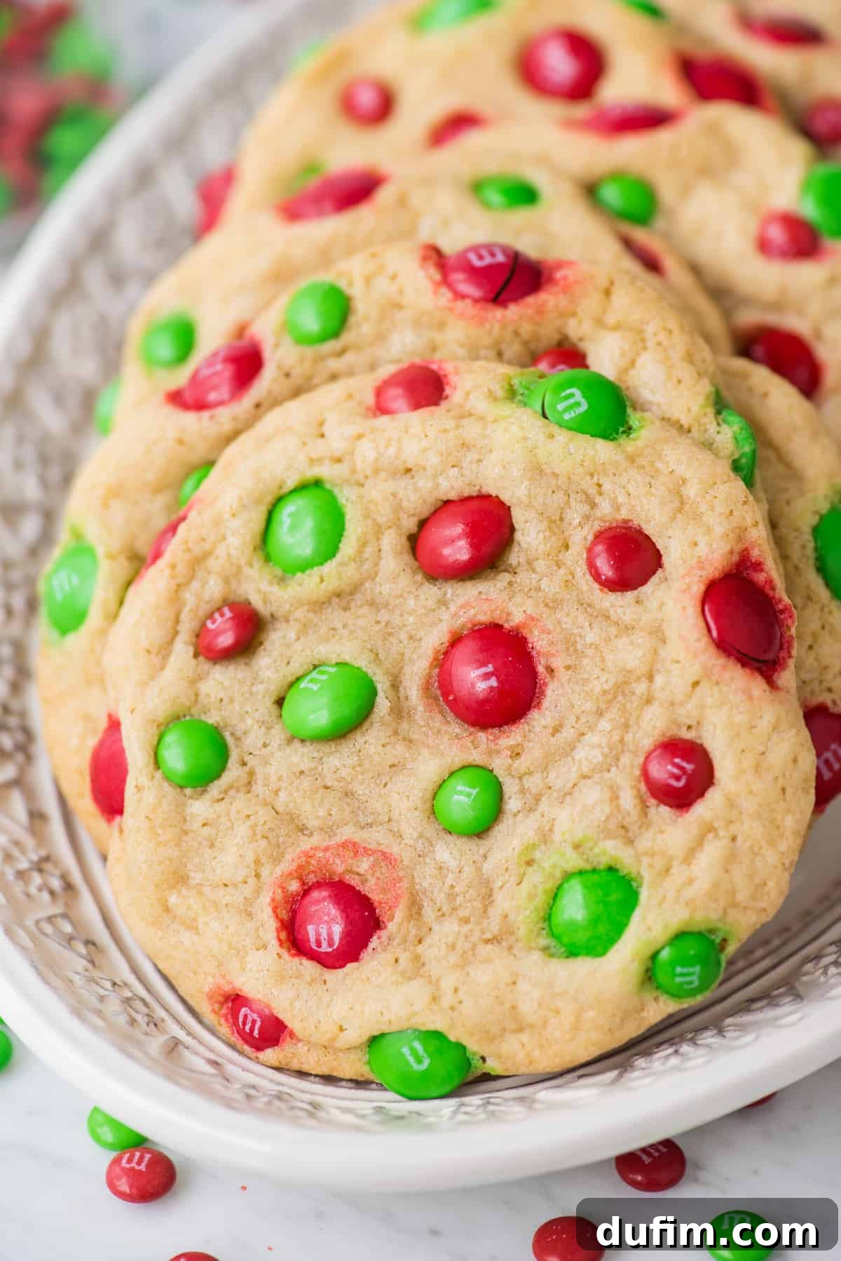 Chewy M&M Cookie Recipe 3 christmas M&M cookies on white christmas platter, festive and vibrant