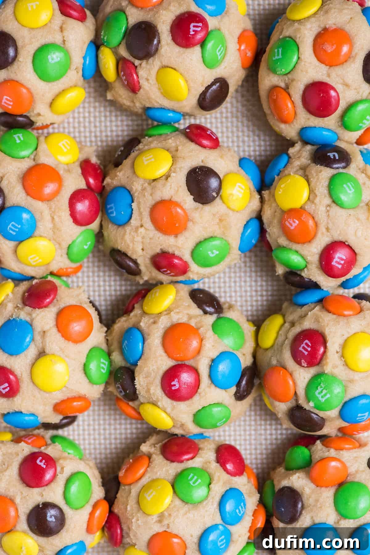 Chewy M&M Cookie Recipe 5 M&M cookie dough balls arranged in a grid pattern on a baking sheet, ready for the oven