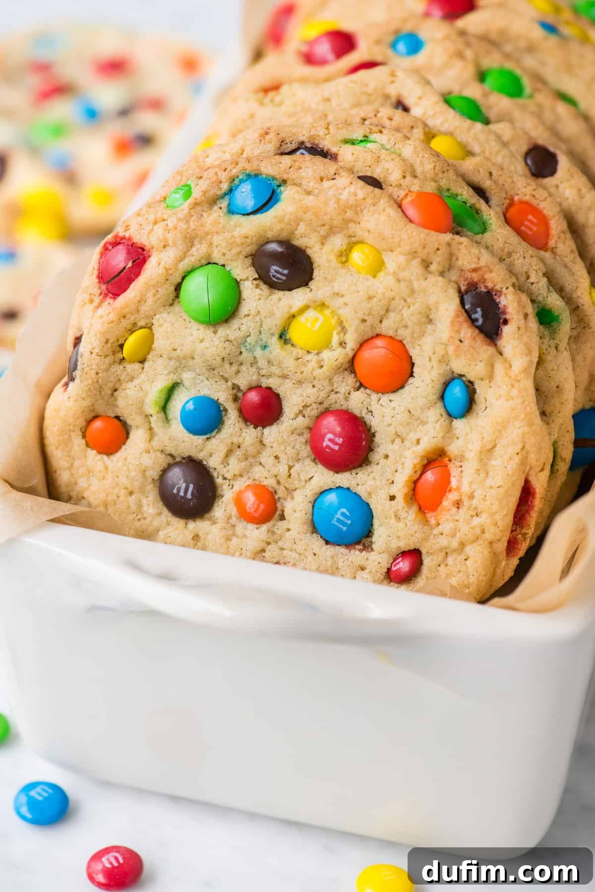 Chewy M&M Cookie Recipe 6 M&M cookies propped up in white loaf pan, showing their soft texture and colorful candies