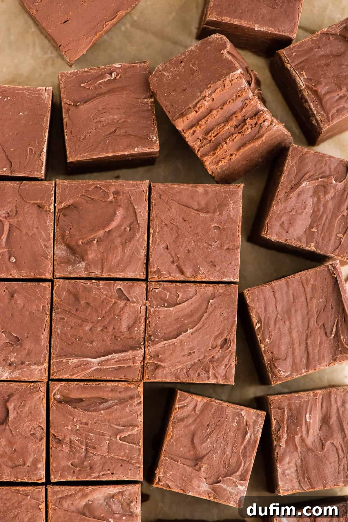 Precisely cut squares of homemade chocolate fudge arranged in a neat grid pattern on brown parchment paper, ready for serving or gifting.