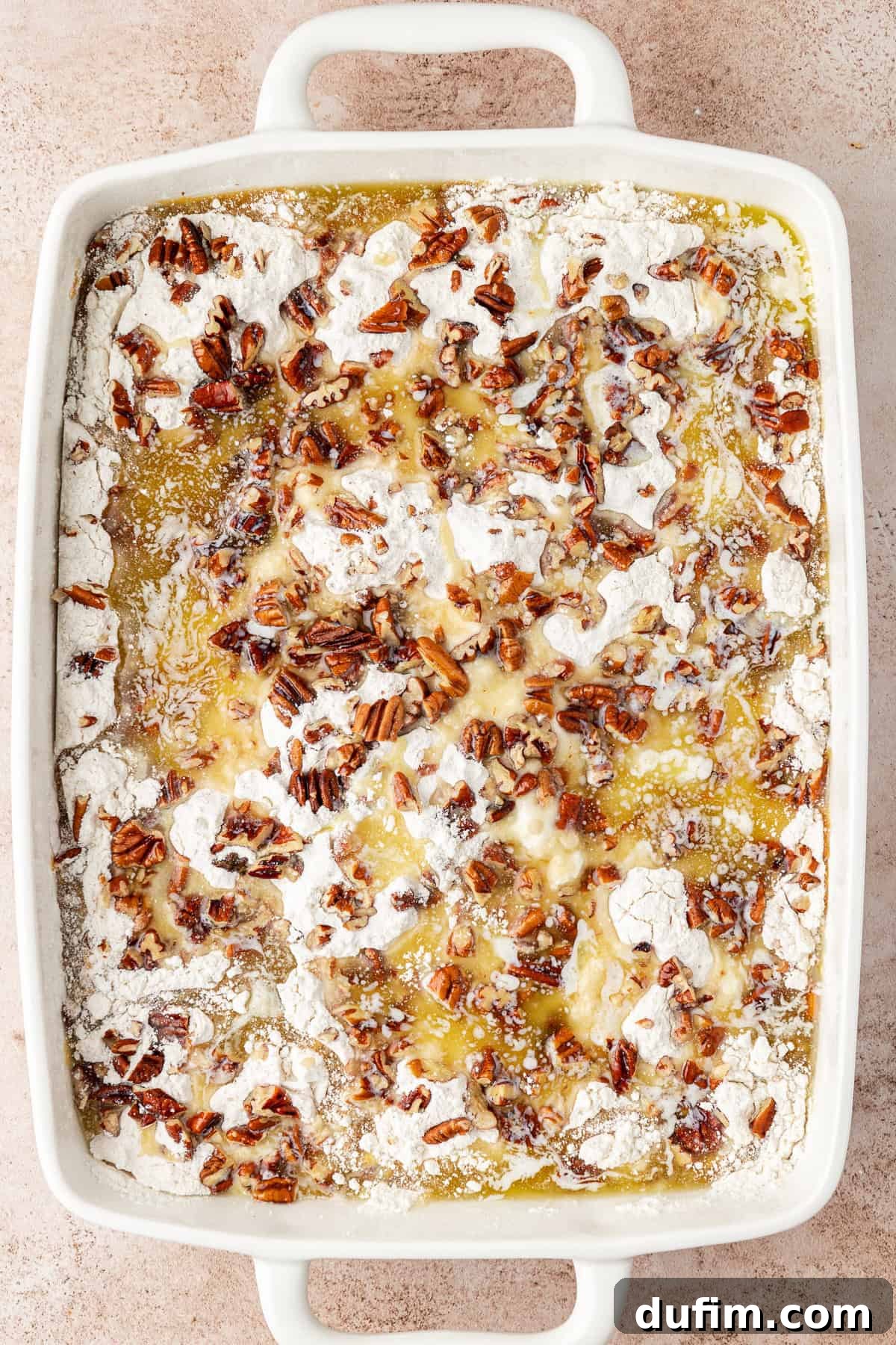 Effortless Autumn Pumpkin Dump Cake 11 Step 5: Drizzling abundant melted butter evenly over the dry cake mix and chopped pecans before placing the pan into the oven.