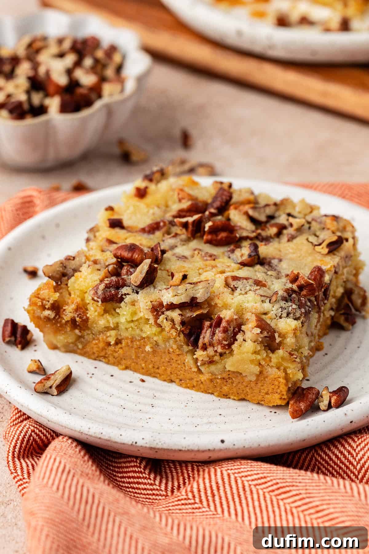Effortless Autumn Pumpkin Dump Cake 4 A close-up shot of a slice of pumpkin dump cake on a pristine white plate, revealing its moist pumpkin layer and perfectly golden, crunchy topping.