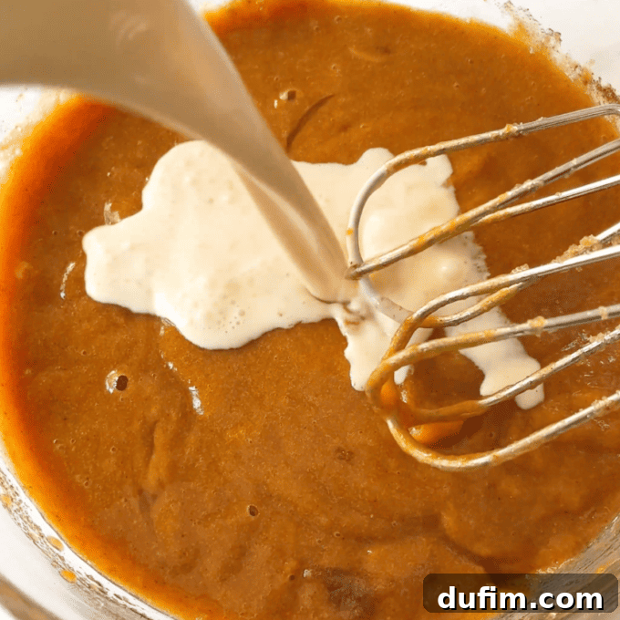 Effortless Autumn Pumpkin Dump Cake 8 Step 1: Whisking the pumpkin mixture vigorously until it becomes smooth and all ingredients are thoroughly combined.