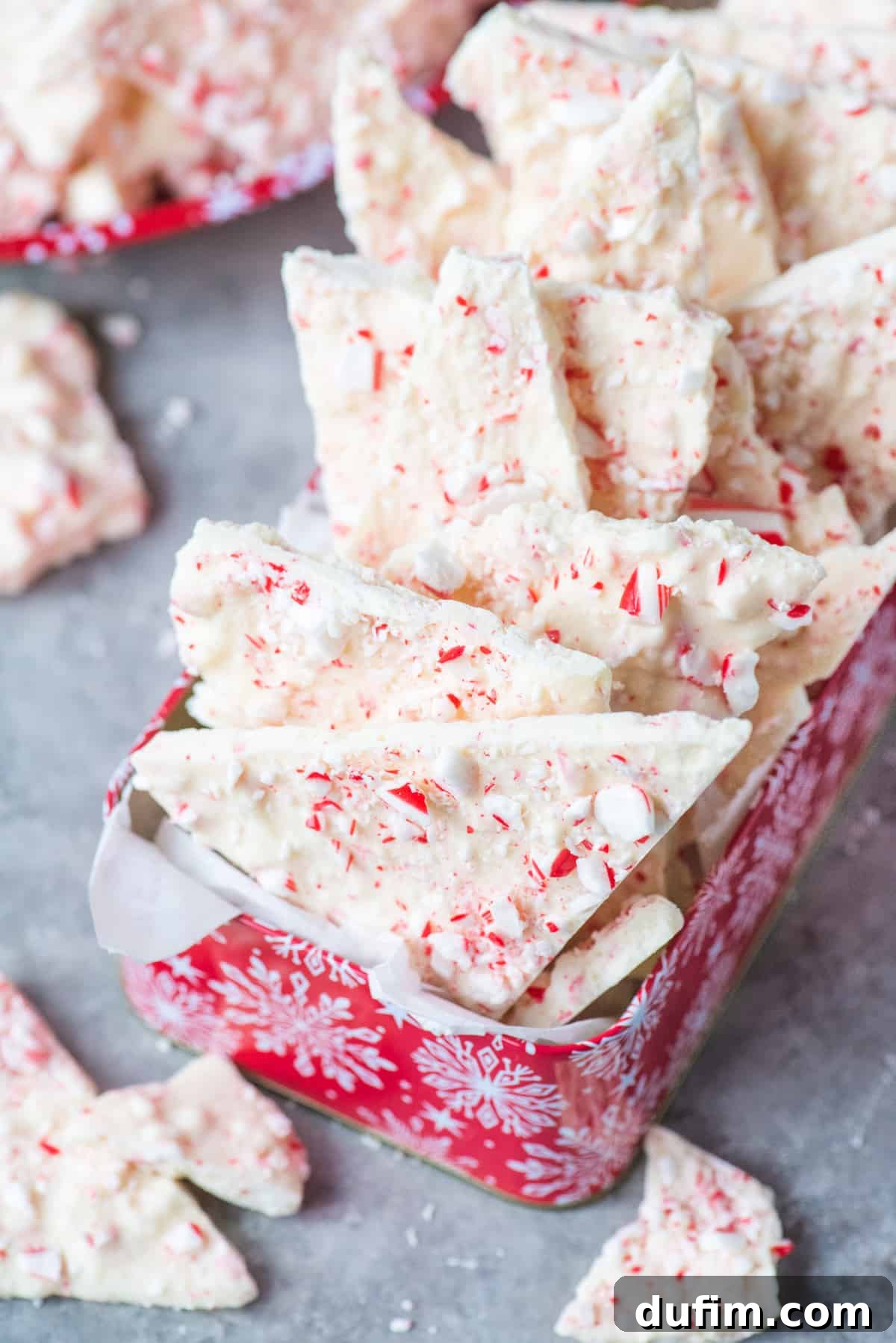 Frosted Peppermint Dream Bark 9 Red Christmas tin filled with delightful white chocolate peppermint bark pieces, ready for holiday gifting.