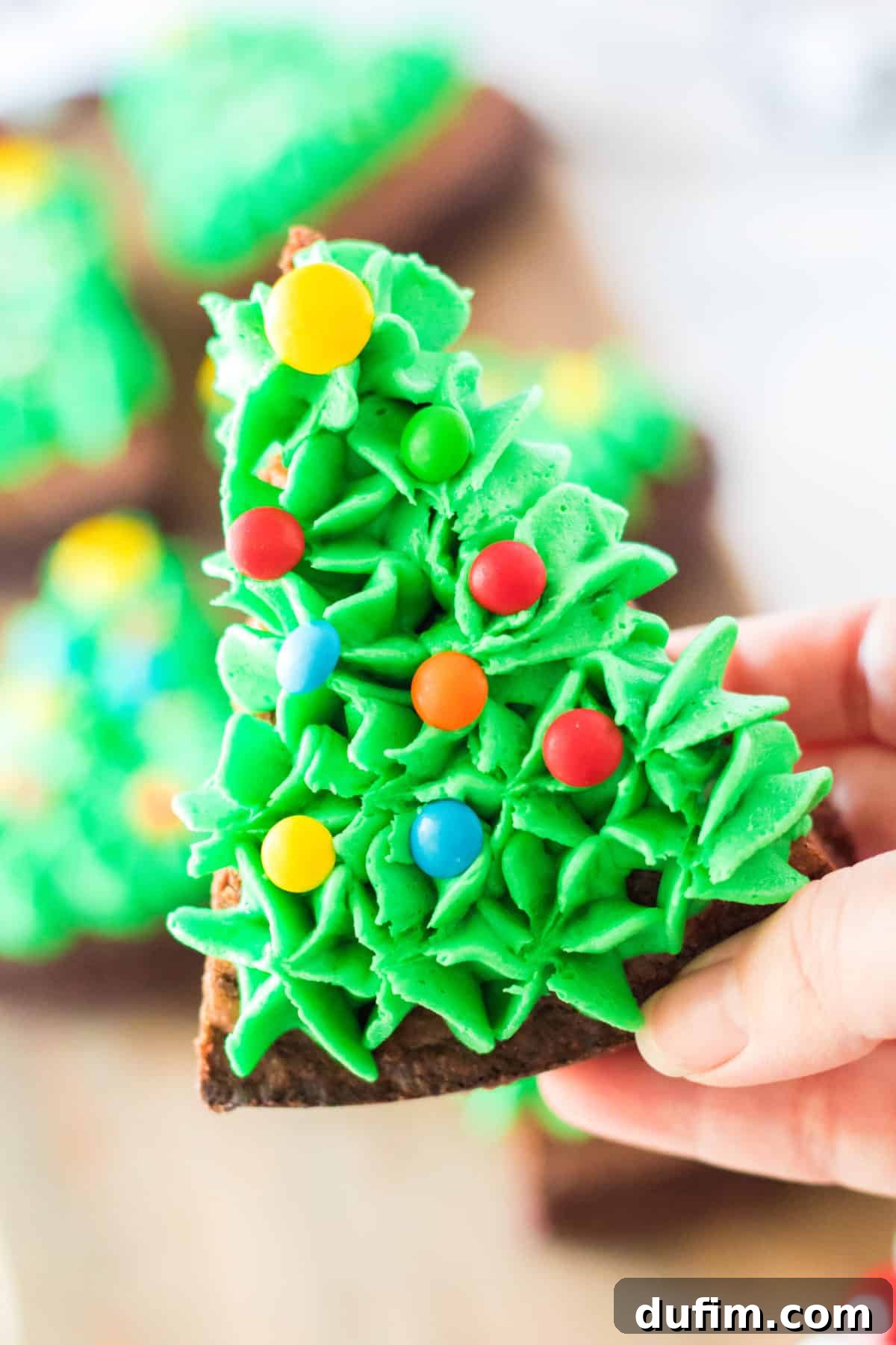 hand holding triangle brownies decorated to look like a Christmas tree