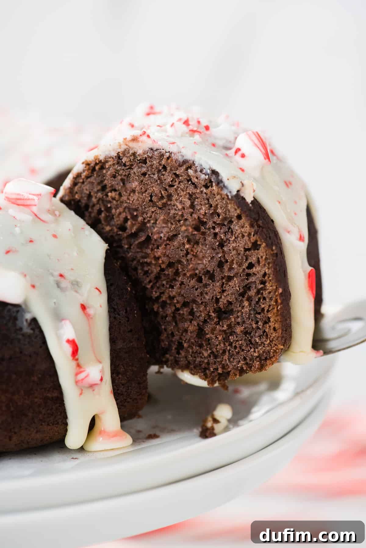 A slice of chocolate bundt cake being carefully lifted from the main cake using a metal spatula, showcasing its perfect form and texture.