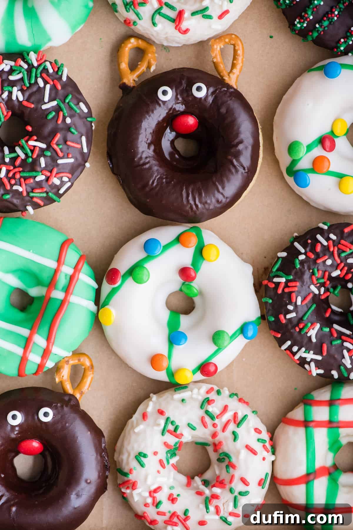 A festive arrangement of 12 Christmas donuts in a grid inside a white donut box, showcasing a variety of colorful and creative holiday decorations, ready to be enjoyed.