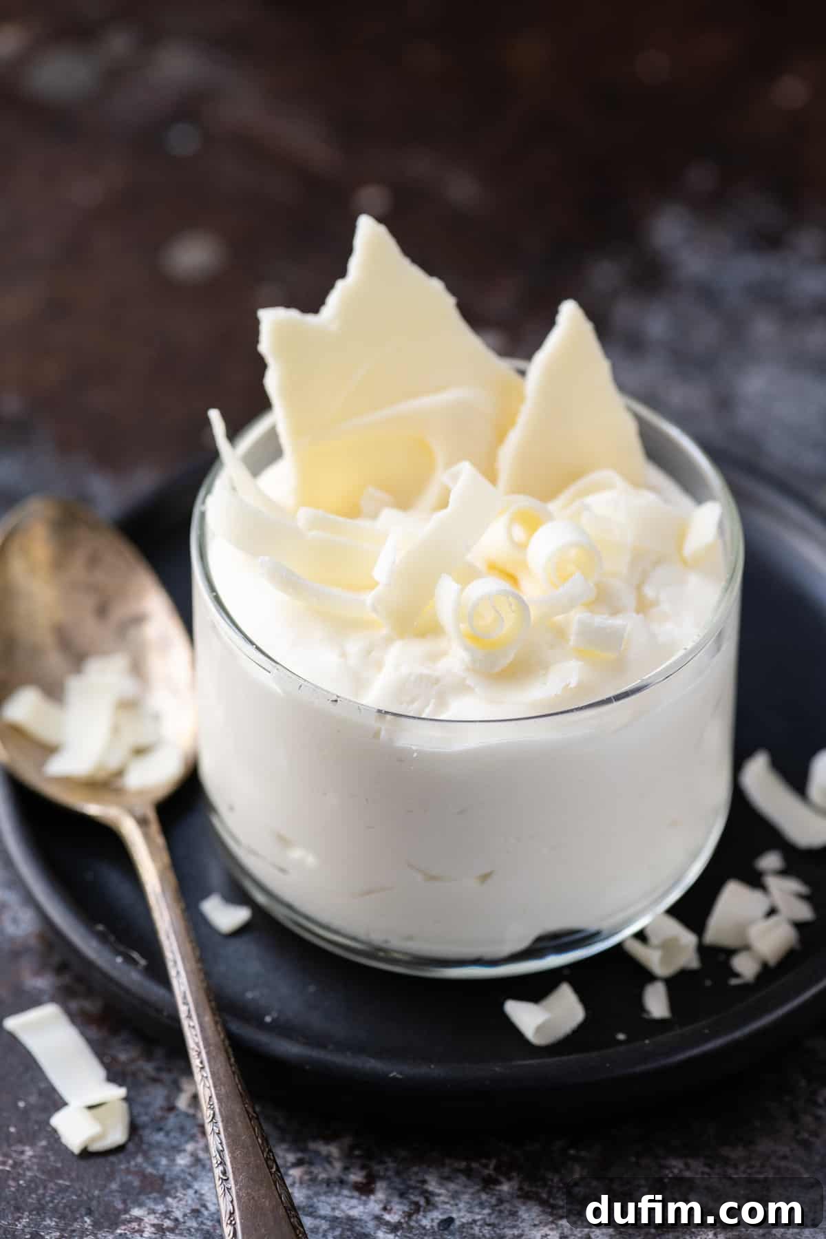 white chocolate mousse in small glass dish on dark plate and dark background