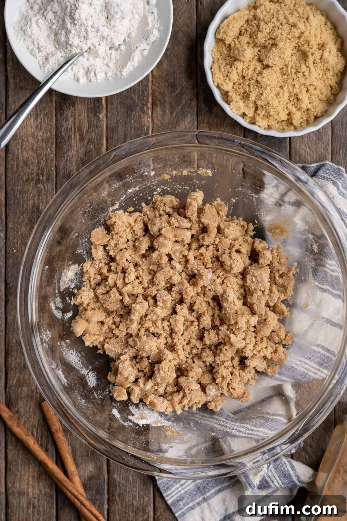 Crumb topping in a glass bowl, ready to be used, resting on a rustic wooden background.