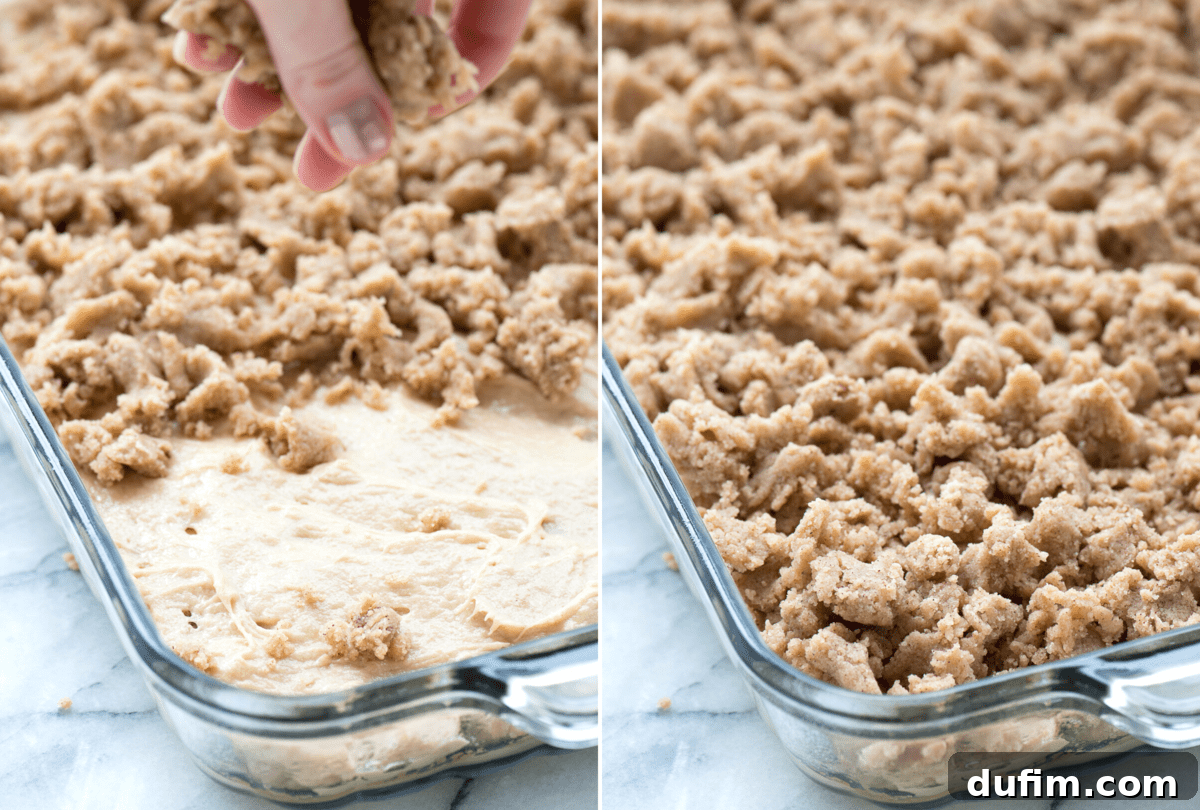 Delicious crumble topping being generously added to a cake batter in a classic glass 9x13 inch baking pan.