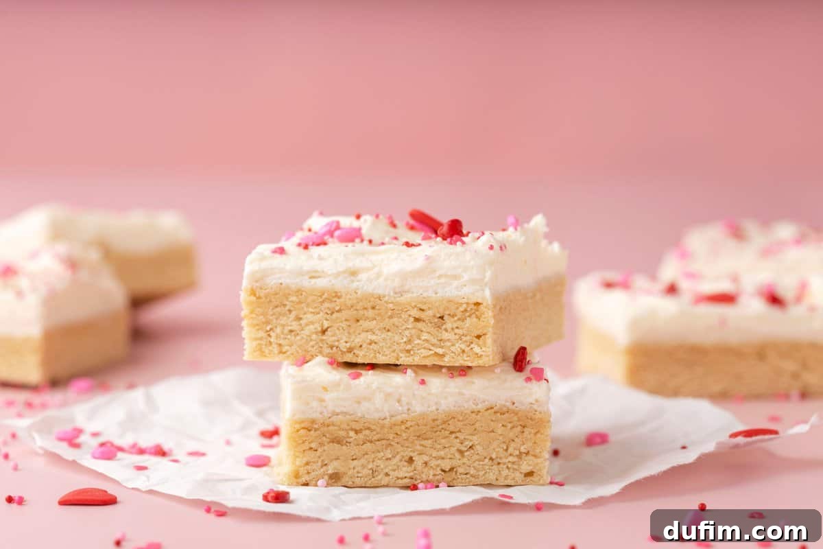 Sweetheart Sugar Cookie Bars 6 A top-down view of two beautifully frosted sugar cookie bars with a scattering of Valentine's themed sprinkles.