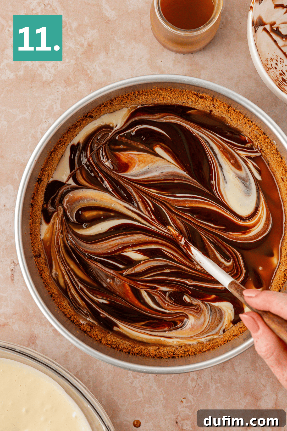 A hand swirls chocolate and caramel into a creamy pie filling in a round crust, creating a marbled pattern. A small jar of caramel and a bowl with remaining filling sit nearby. The image is labeled 11. in a green box.