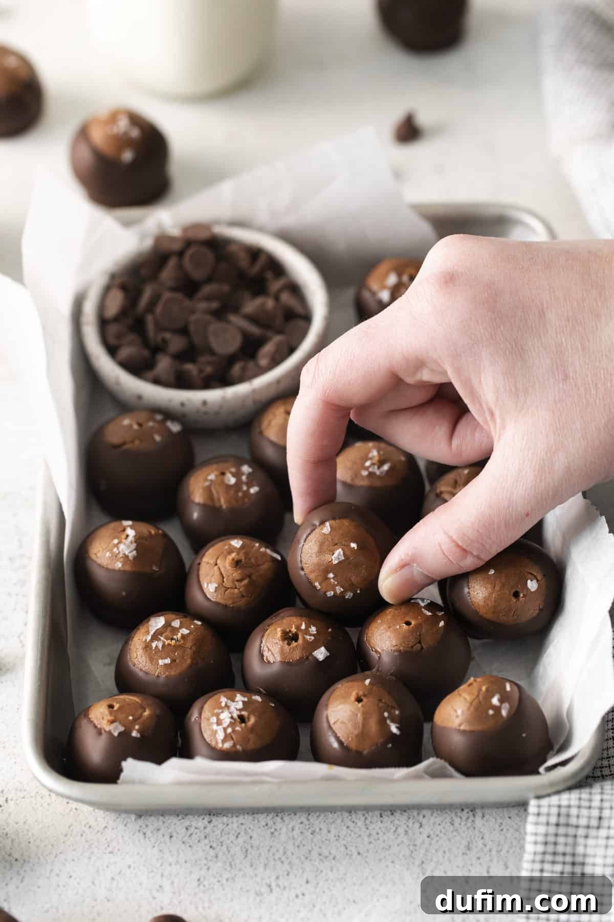 Decadent Nutella Buckeye Bites 2 Nutella buckeye balls arranged neatly on a metal baking sheet with white parchment paper, ready to be served or stored.