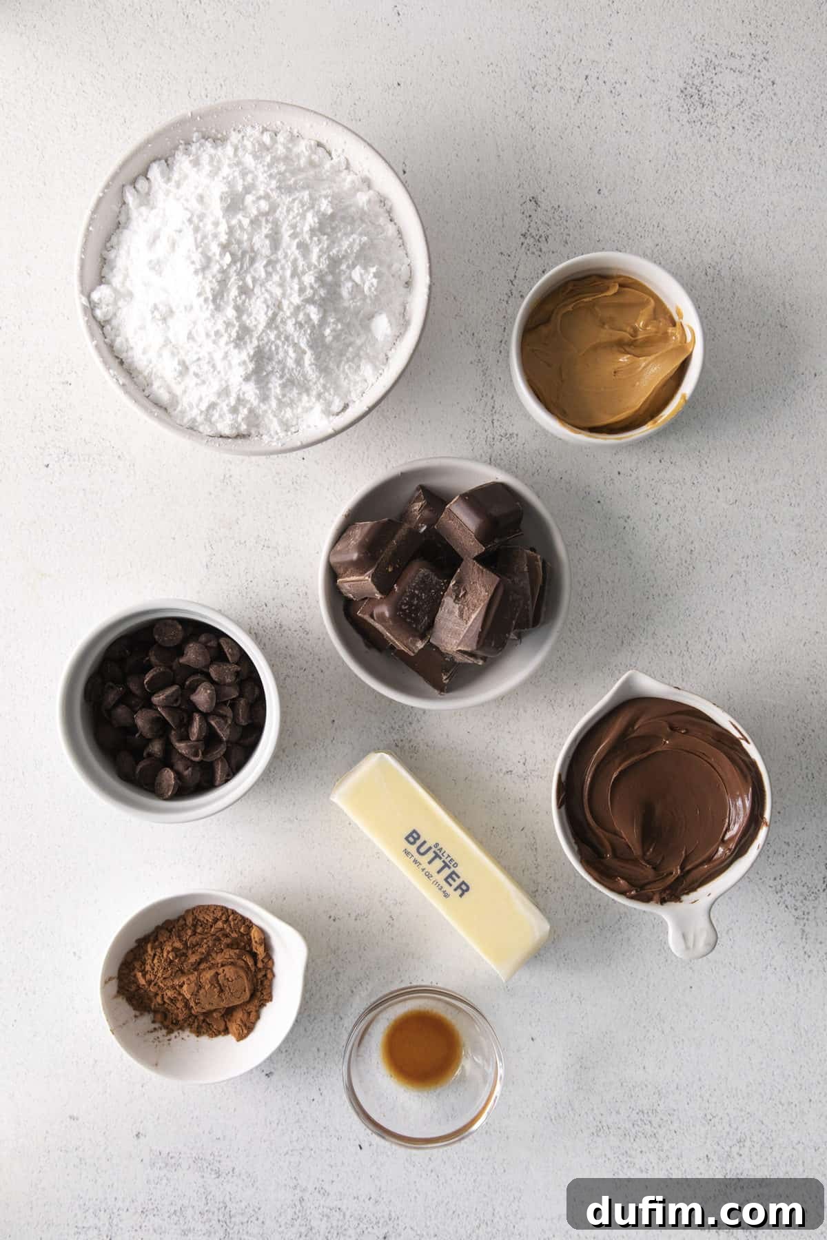 Decadent Nutella Buckeye Bites 3 Ingredients laid out on a white background, including Nutella, peanut butter, powdered sugar, butter, vanilla extract, cocoa powder, chocolate almond bark, and dark chocolate chips, for making chocolate buckeyes.