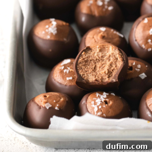 Decadent Nutella Buckeye Bites 7 A tray of chocolate truffles topped with flaky sea salt, featuring one center truffle with a creamy chocolate filling and a bite taken out—perfect for fans of nutella buckeye balls or those seeking a new buckeye recipe.