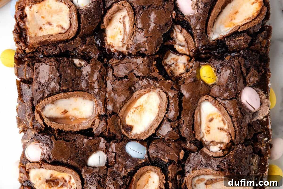 A decadent close-up shot of Cadbury Creme Eggs perfectly baked into the surface of rich, fudgy brownies, showing the signature gooey filling.