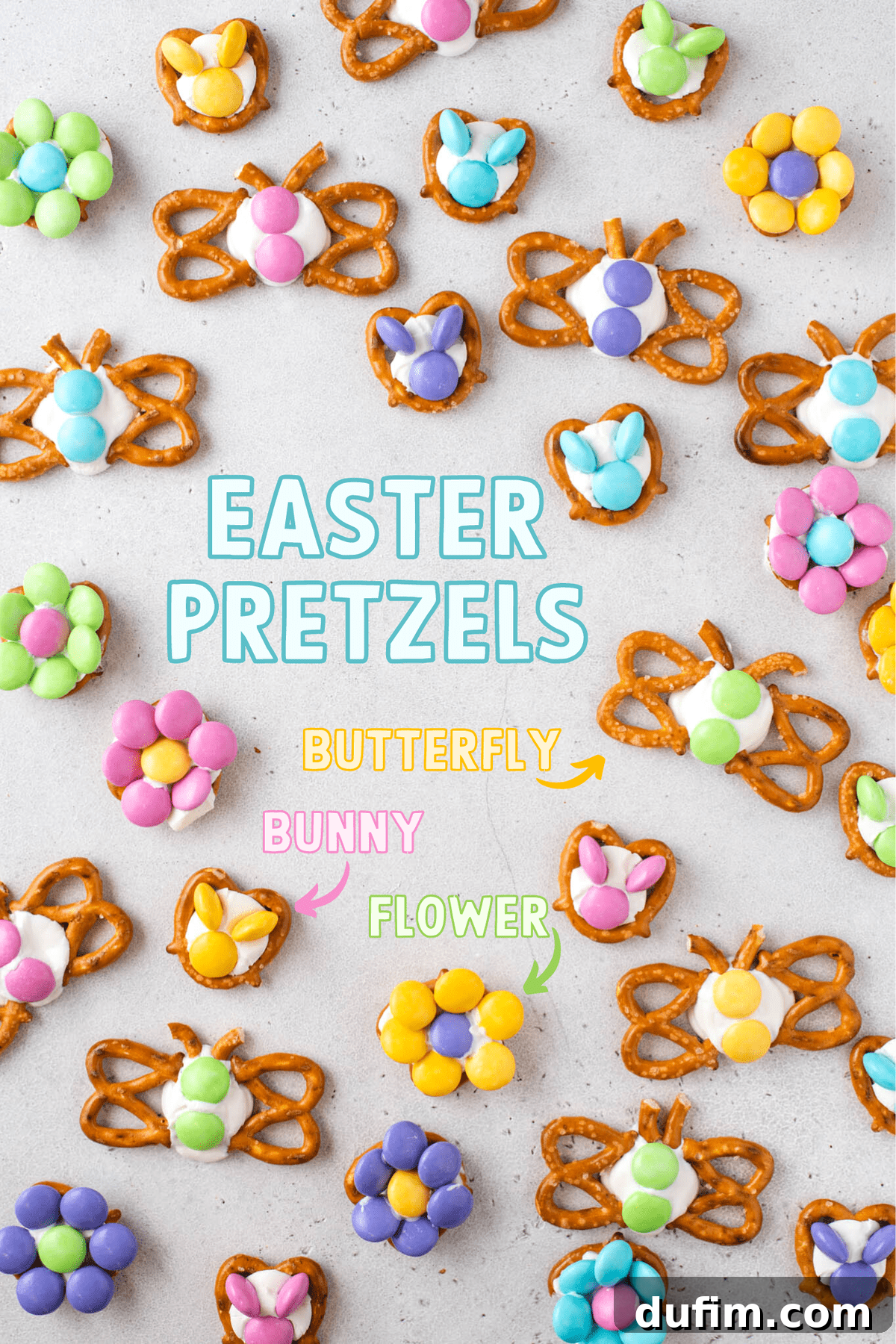 Assortment of colorful Easter pretzels shaped as butterflies, bunnies, and flowers, arranged beautifully on a gray background, showcasing the ease of creation with pretzels, candy melts, and M&M's.