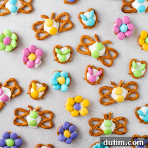 Colorful spring-themed Easter pretzels made with white icing and pastel candies, arranged in butterfly and flower shapes, make delightful Easter treats on a light gray surface.