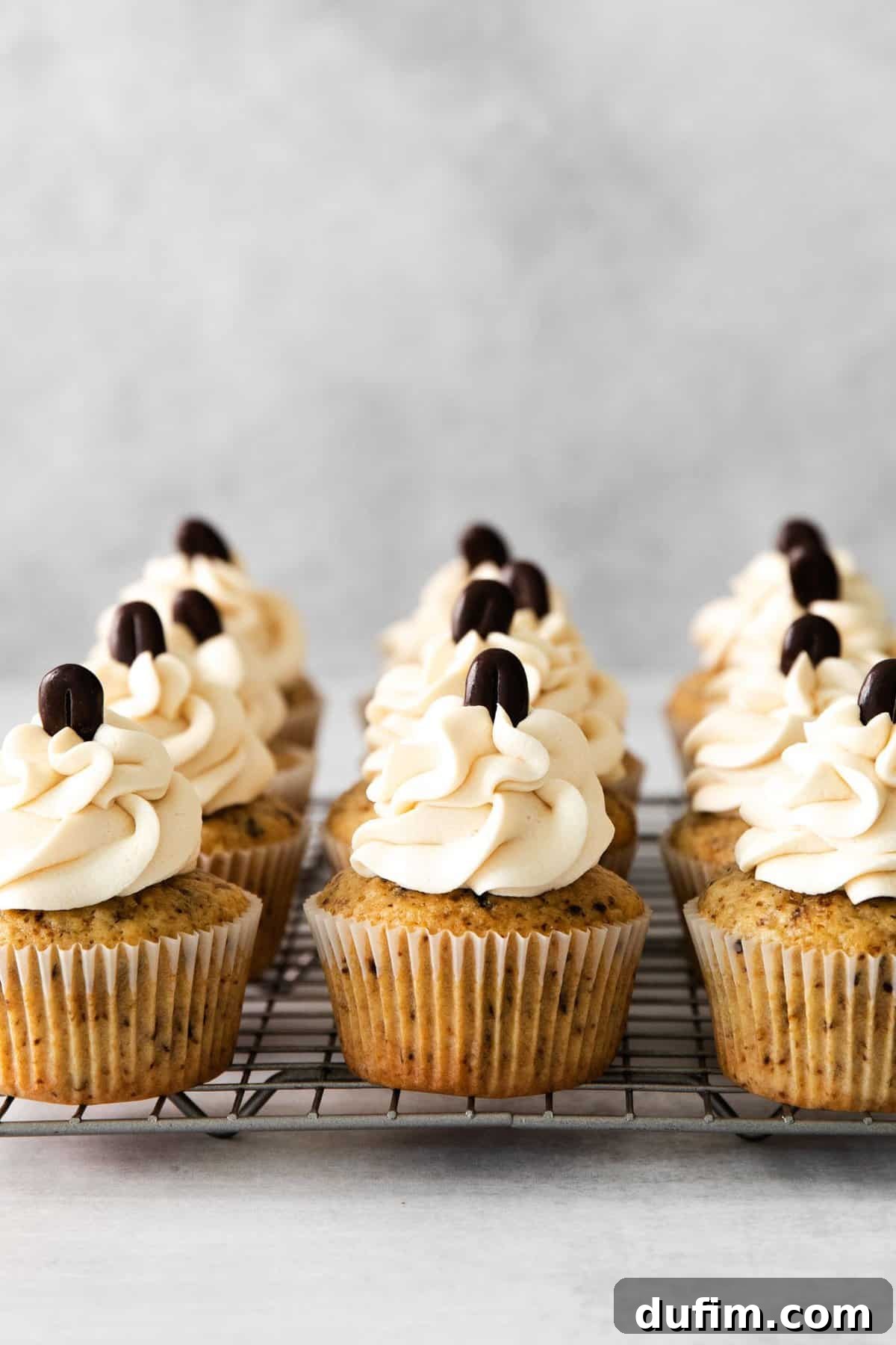 Freshly baked coffee cupcakes cooling on a wire rack, ready for frosting.