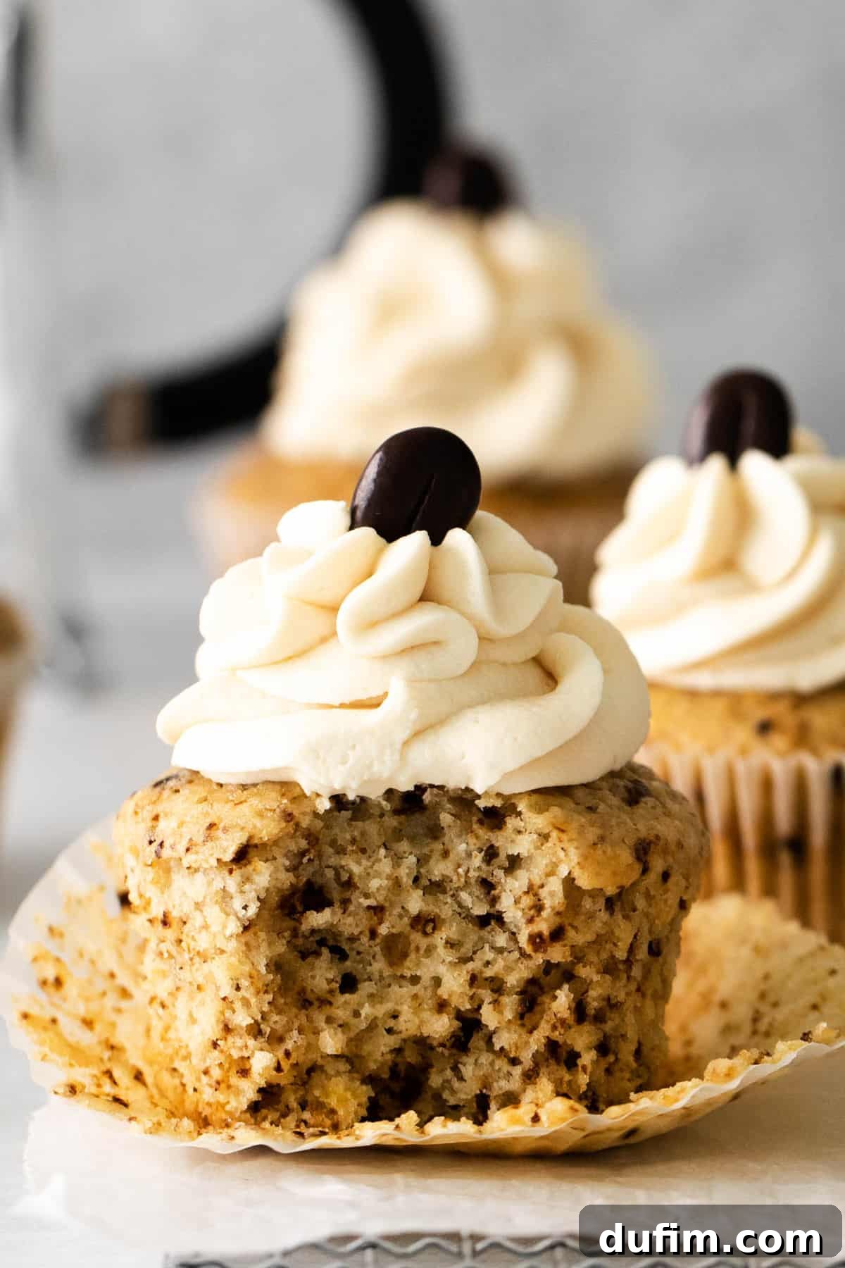 A perfectly baked mocha cupcake with a bite taken out, revealing its moist interior, adorned with coffee frosting.