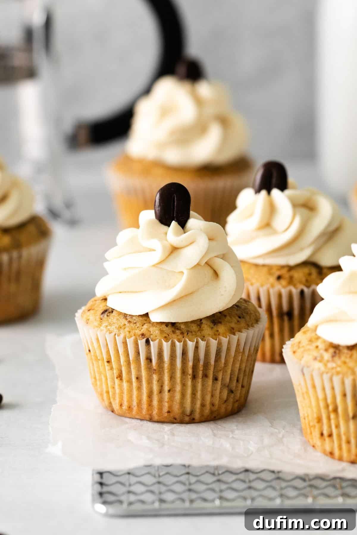 A trio of espresso cupcakes, elegantly frosted with coffee buttercream and topped with a single coffee bean garnish.
